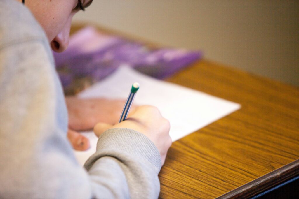 student writing on paper on desk